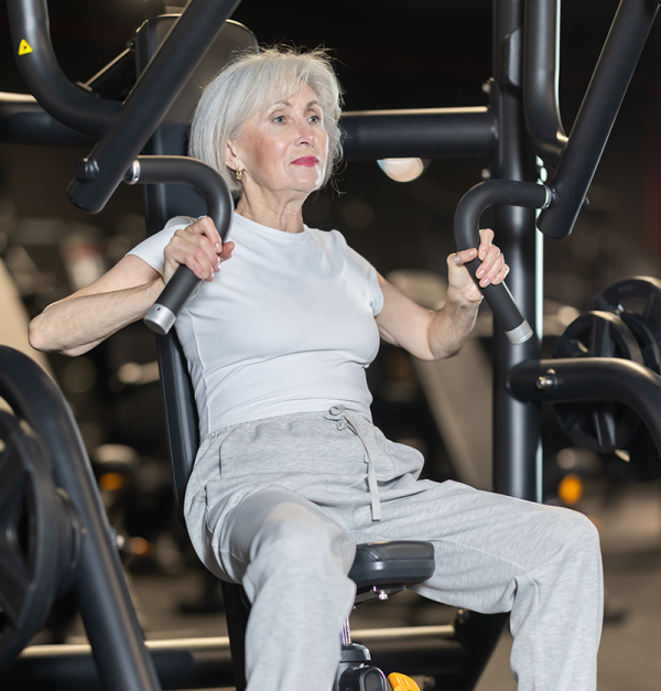 middle aged woman pushing weights in gym